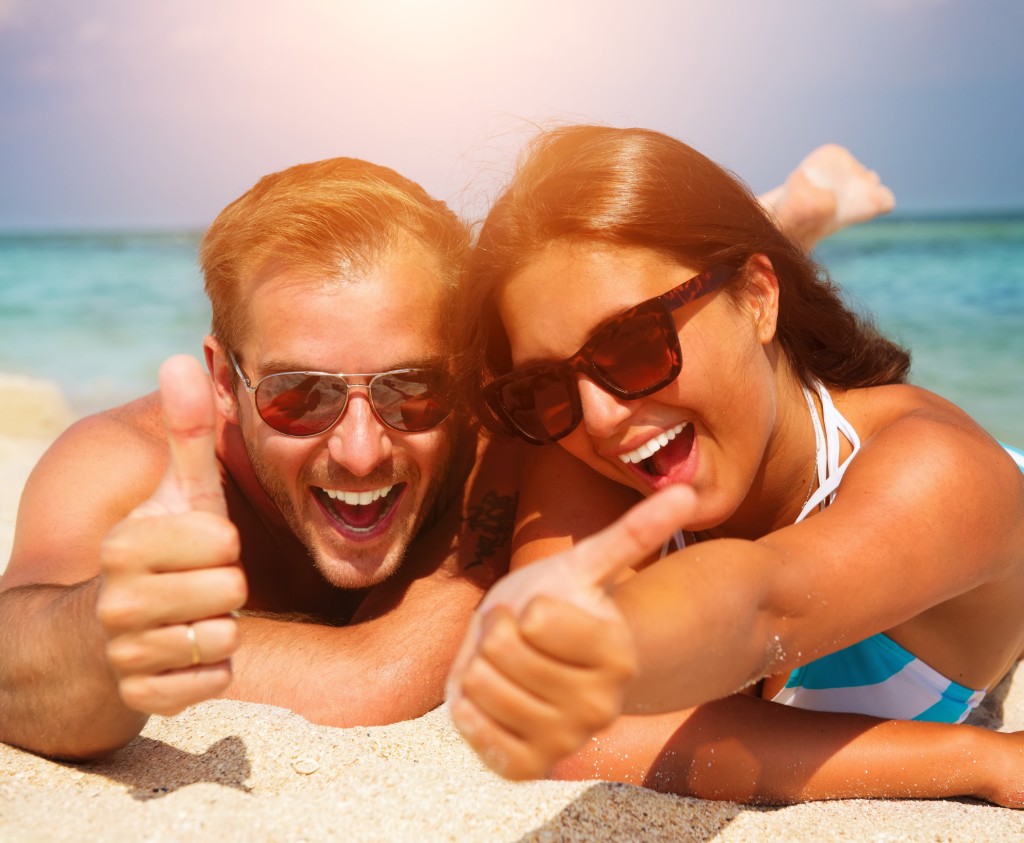 Couple Enjoying On The Beach Wearing Black Glasses